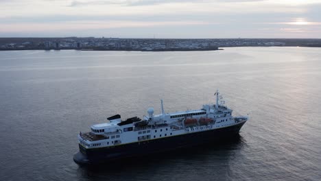 natgeo explorer boat calmly floating with iceland reykjavik in background, cloudy day