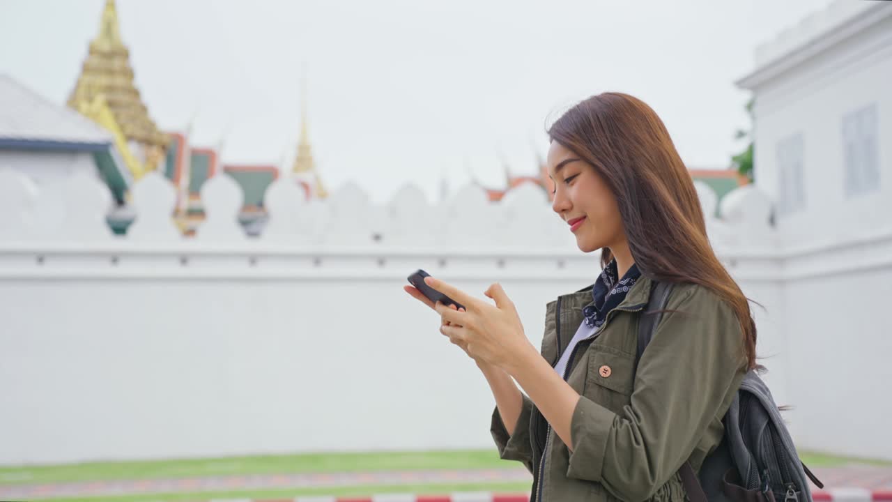 아시아의 매력적인 여성 배여행자는 도시를 는 동안 전화로 이야기합니다. 아름다운 여성 관광 여행자는 스마트폰을 사용하여 거리에서 혼자 여행합니다. 태국에서 휴가 휴가 여행을 즐기십시오.