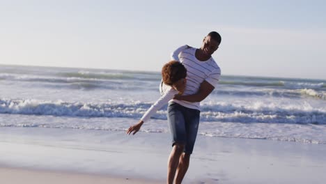 African-american-father-picking-up-his-son-and-playing-at-the-beach