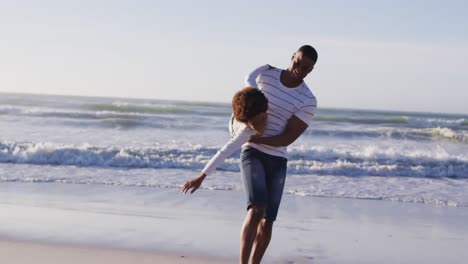 padre afroamericano recogiendo a su hijo y jugando en la playa