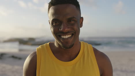 retrato de un hombre afroamericano guapo y en forma sonriendo con confianza en la playa con chaleco amarillo