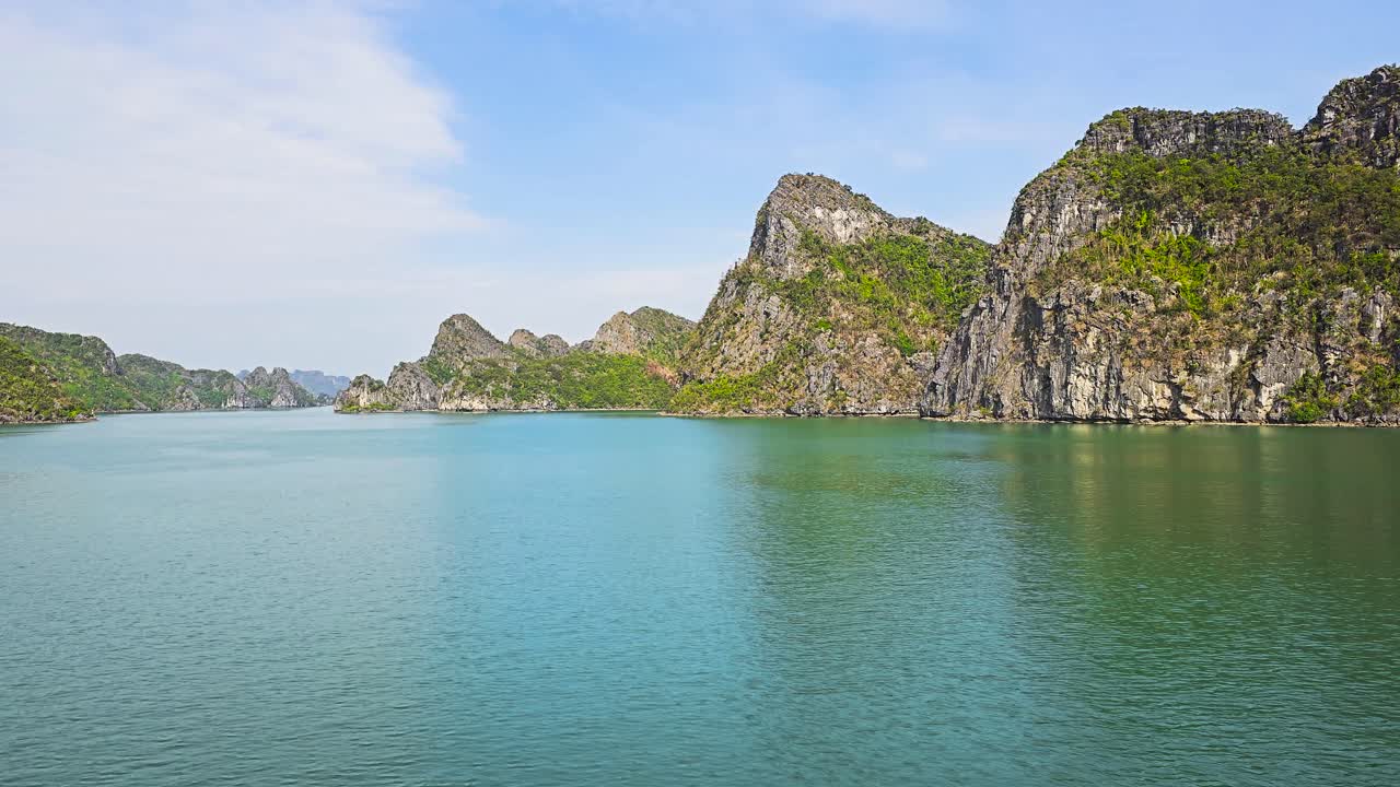 Majestic limestone karsts rise dramatically from the emerald waters of Ha Long Bay, creating a mesmerizing seascape of towering cliffs and scattered islets