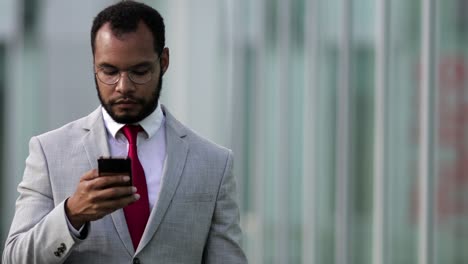 front view of focused businessman using smartphone during stroll