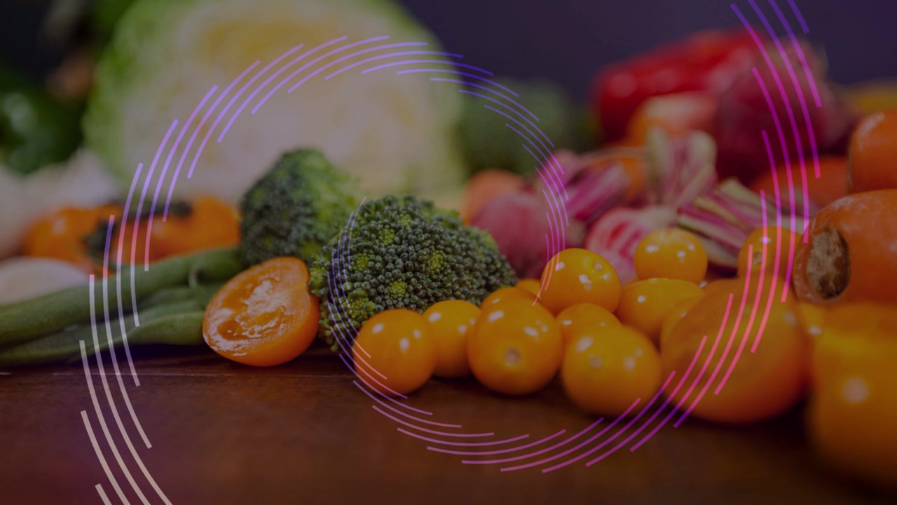 In scena, broccoli e pomodori rimangono immobili mentre anelli ruotano e pulsano, evidenziando il colore.