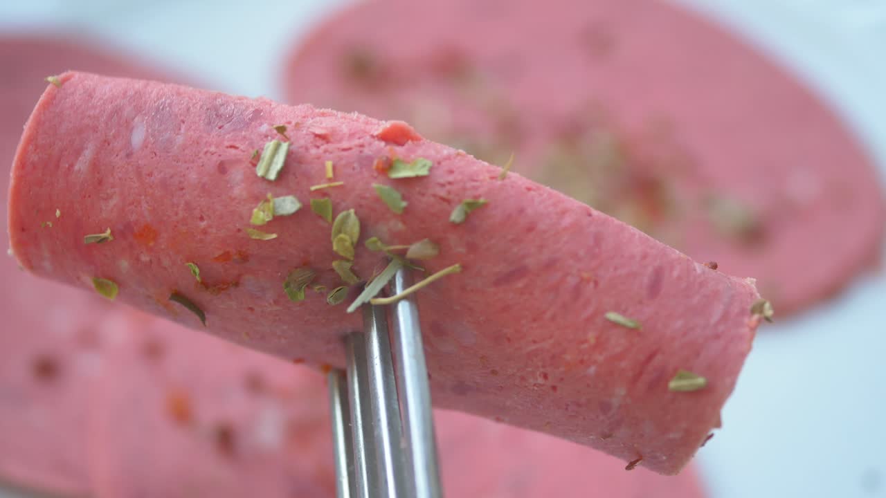 salchicha rosada en rodajas en un tenedor