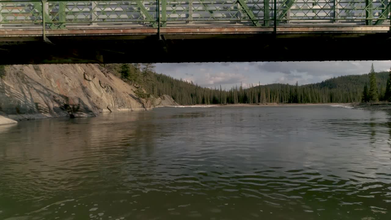 Canadian river in the Rocky Mountains. Aerial drone footage underneath a bridge.