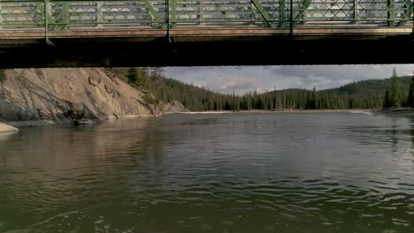 canadian river in the rocky mountains. aerial drone footage underneath a bridge.