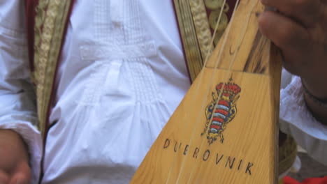 man plays croatian musical instrument in dubrovnik