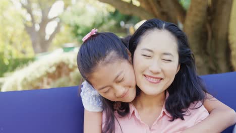 Daughter-hugging-mother-behind-in-garden-4k