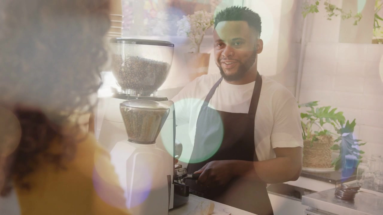 Cliente che effettua un ordine, barista che macina il caffè nel portafiltro mentre sorride e parla.