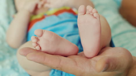 Pies-Pequeños-Pies-De-Bebé-En-Una-Gran-Palma-Padre-El-Concepto---Cuidado-Y-Protección-Una-Infancia-Feliz