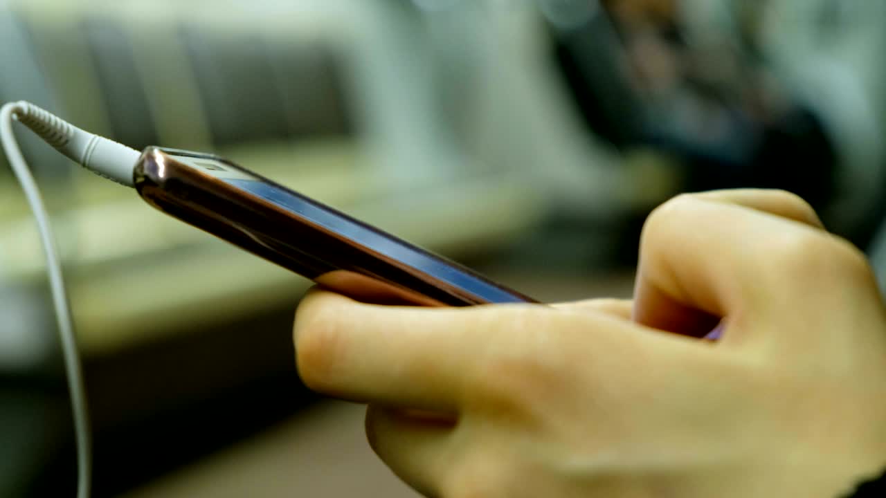 mujer con auriculares usando un teléfono inteligente en el metro en primer plano