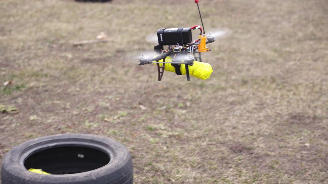 Drone flying low across dirt field showing controlled movement and payload system in operation