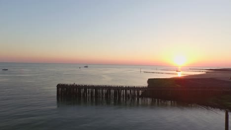 Aerial:-The-pier,-beach-and-lighthouse-during-sunset-near-the-village-Westkapelle,-the-Netherlands