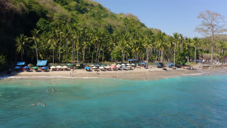 Crystal-Bay-Beach,-Nusa-Penida-in-Bali-Indonesia-cinematic-drone-footage-flyover-amazing-tropical-Hidden-Beach-with-Volcano-sand-and-Palm-tree-forest-next-to-Indian-Ocean-in-Blue-clear-color