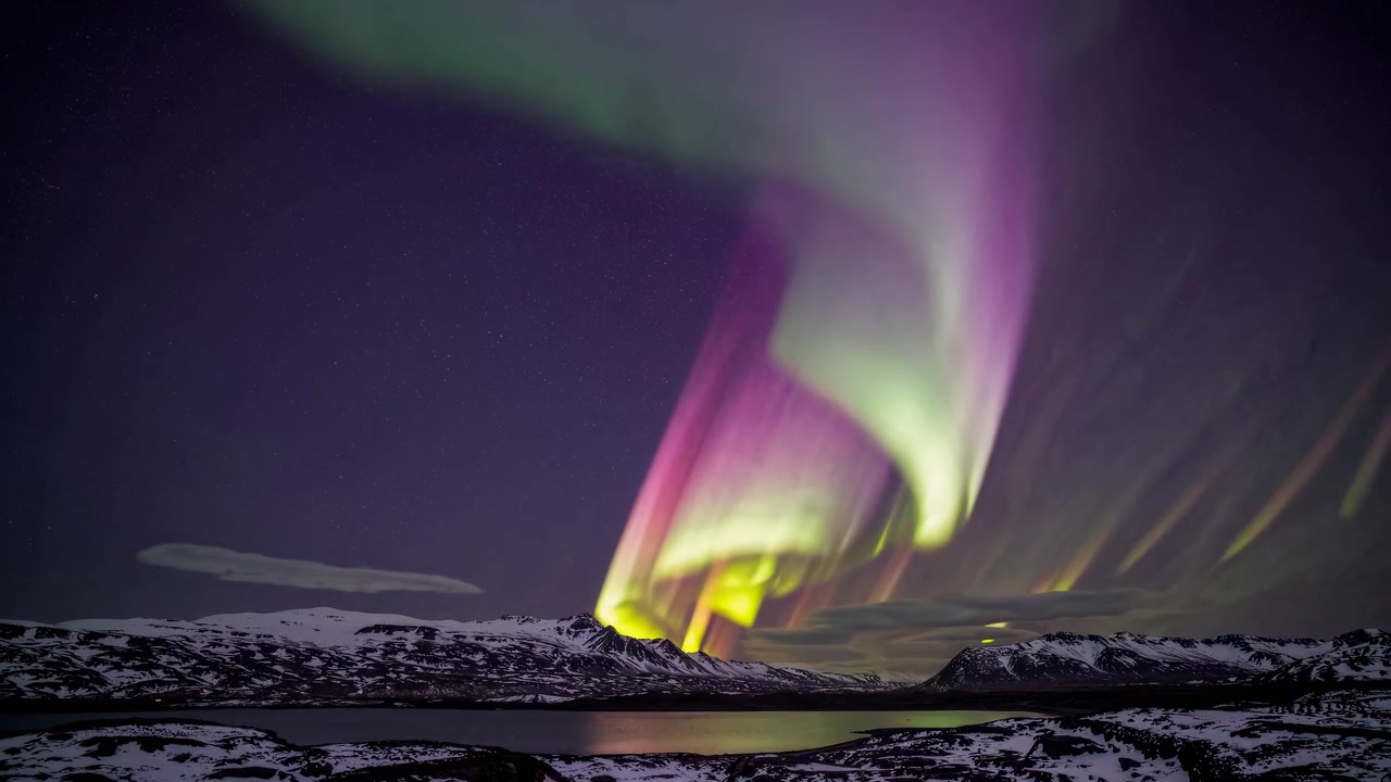 Vibrante aurora boreale che danza su montagne innevate e lago