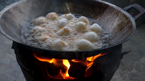 hard boiled duck eggs deep frying in wok above fire stove, close up