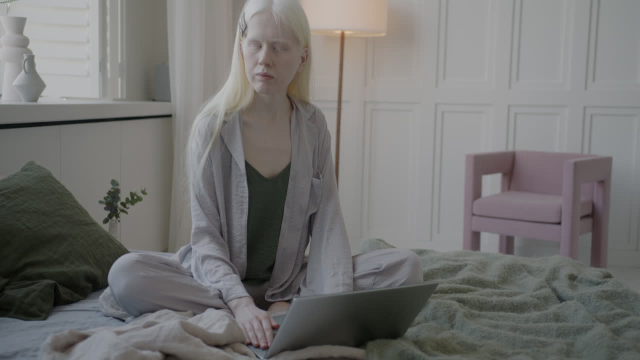 женщина работает на ноутбуке в спальне.
