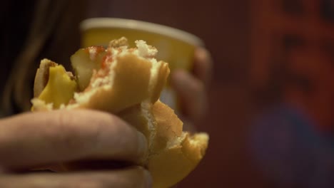 mujer sosteniendo hamburguesa con queso y café primer plano