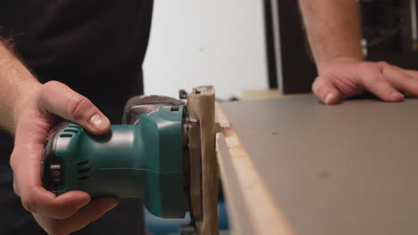 Worker-grinds-wooden-workpiece-edge-in-carpentry-workshop