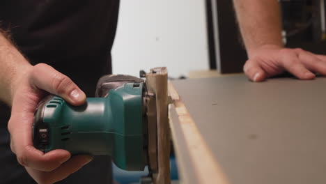 worker grinds wooden workpiece edge in carpentry workshop