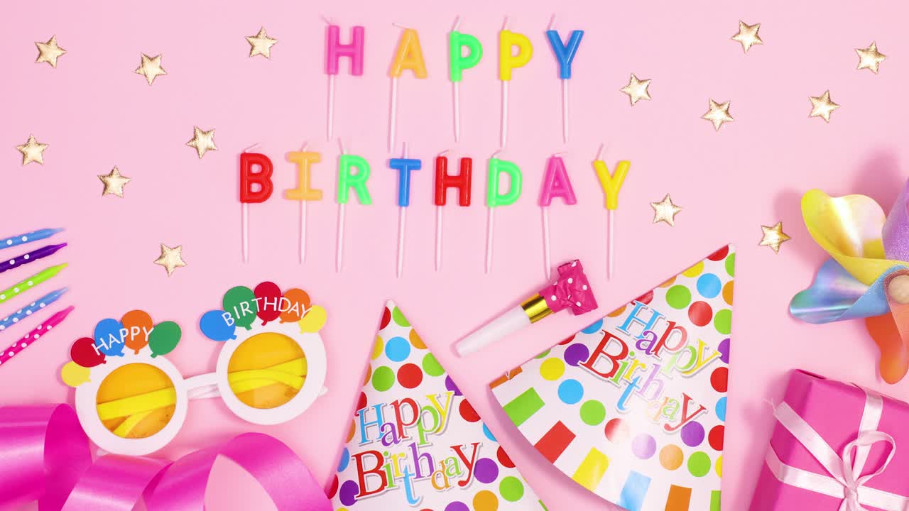 Party decorations and accessories appear with Happy birthday candles on pastel pink theme. Stop motion