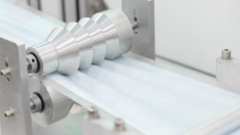 máquina automatizada hace goffering en tira de tela azul para máscaras quirúrgicas - protección para el virus de la corona - inclinación hacia abajo, cámara lenta