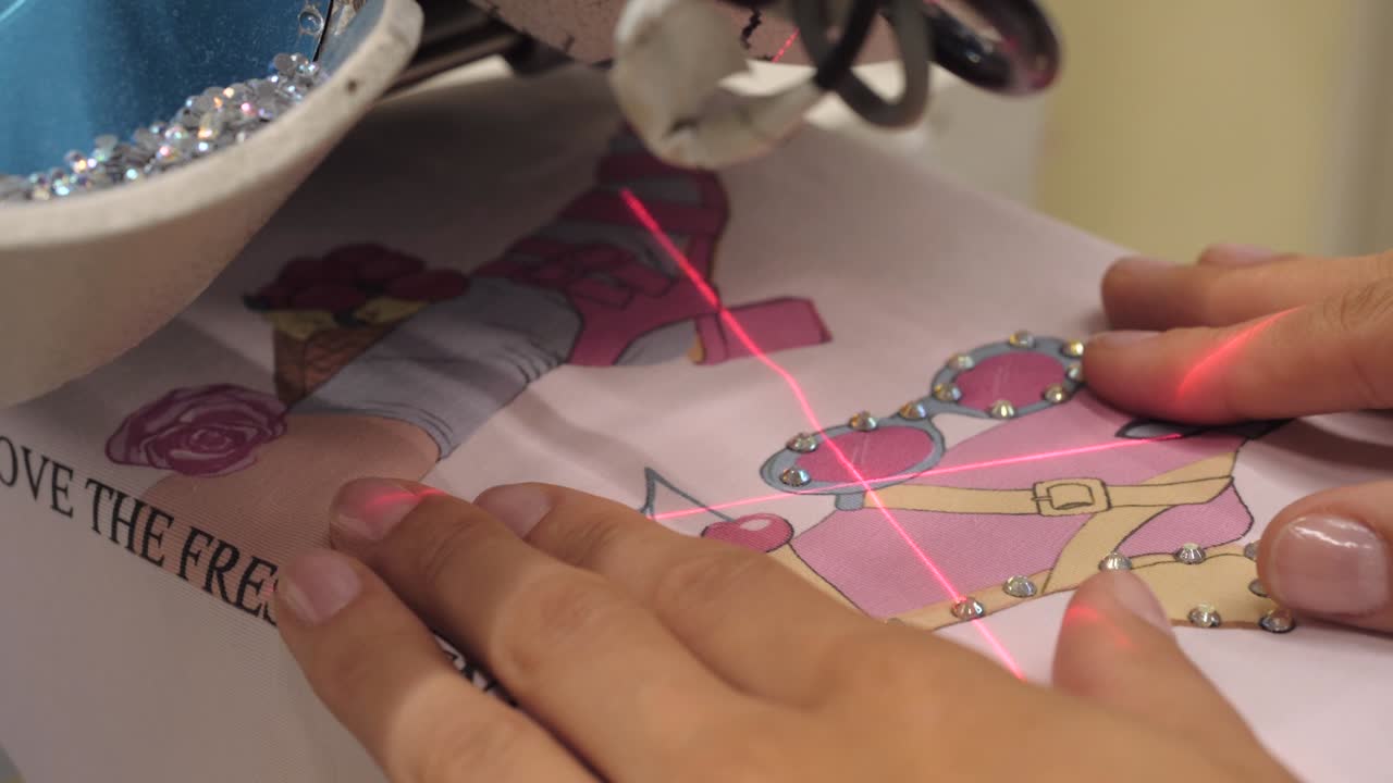 el proceso de aplicar rhinestones a la ropa utilizando una máquina industrial.