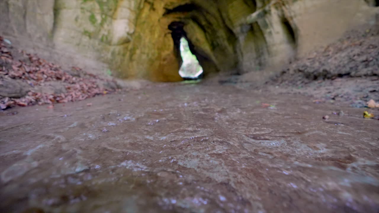 tiro en ángulo bajo de un arroyo natural que fluye a través de una cueva durante un día soleado en otoño