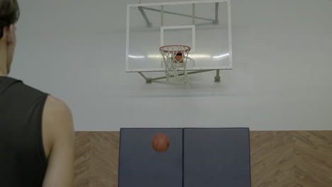 over the shoulder shot of man shooting basketball and making basket