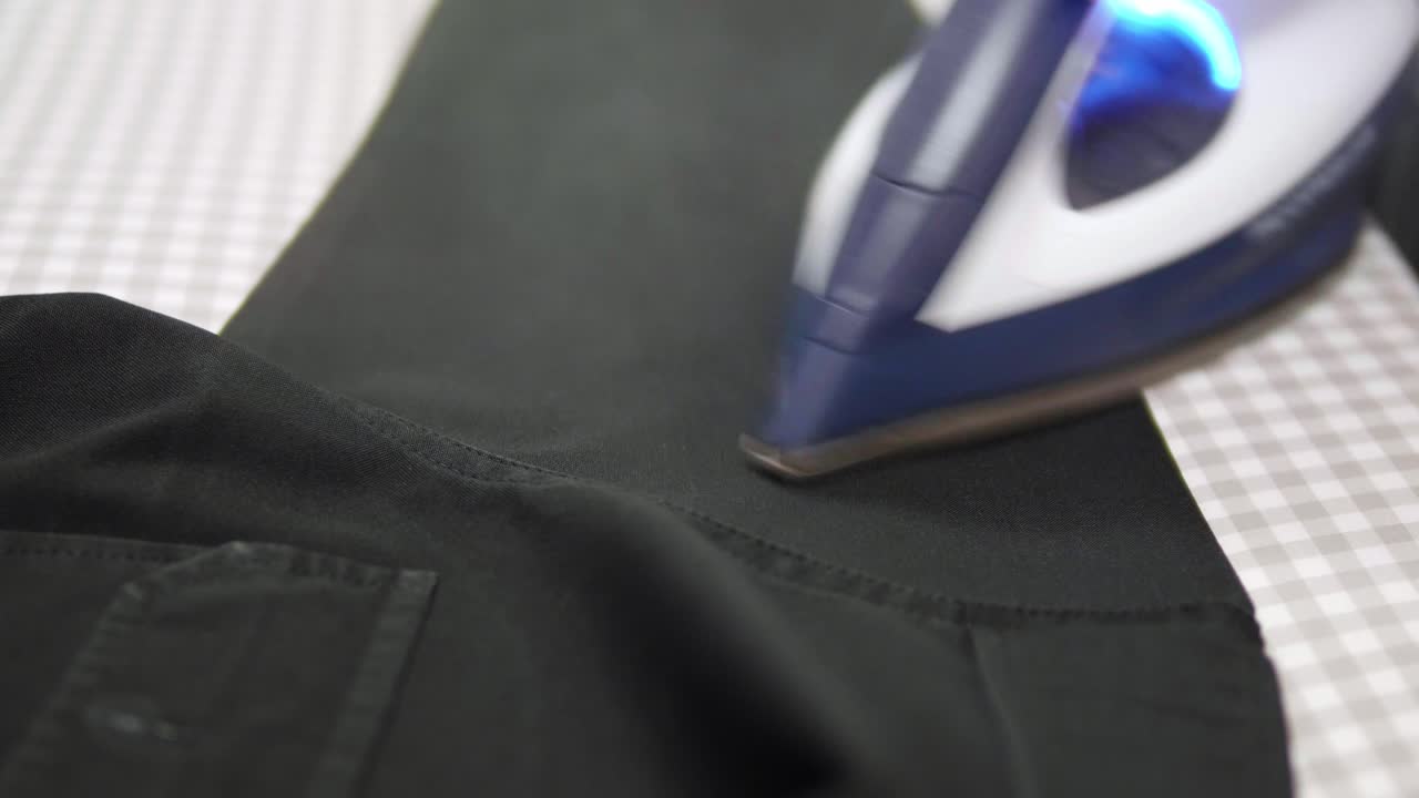 Closeup of a woman ironing clothing by stream iron on board at home with slow motion scene
