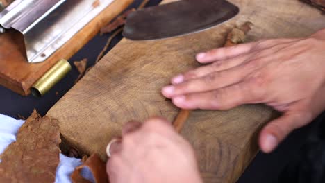 overhead close up of aged and wrinkled hands rolling a cigar in the caribbean