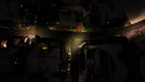 quiet american residential area during winter snow at night. warm lighting lantern and streetlights on road. snowy houses and single family homes. aerial top down shot.