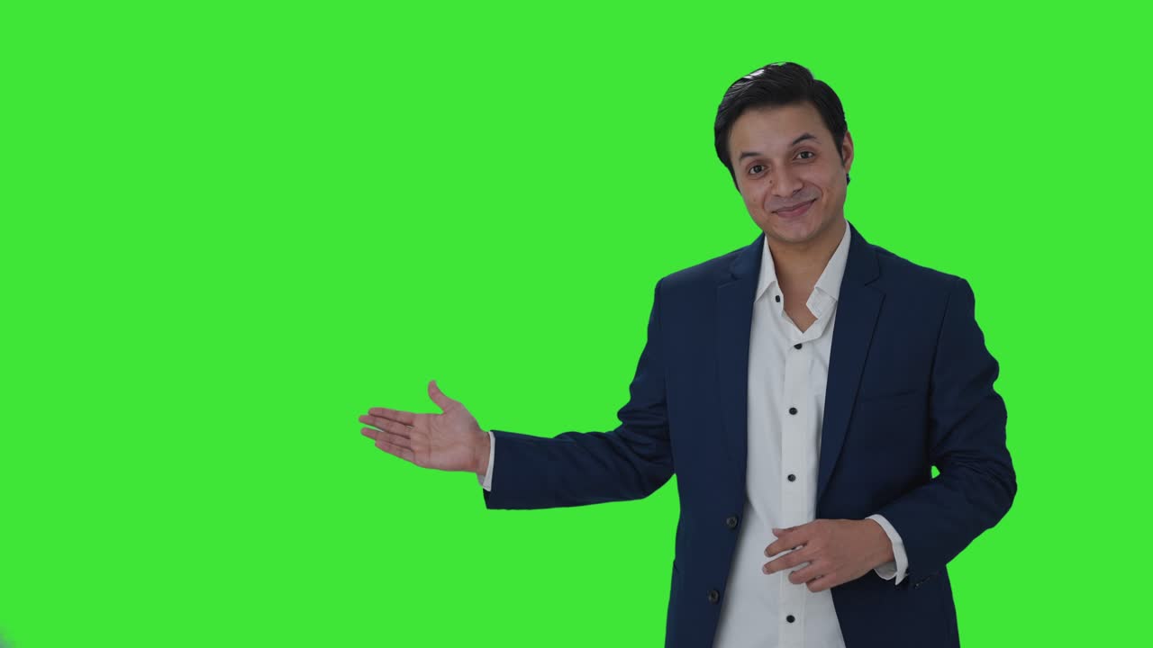 periodista indio feliz señalando el espacio de copia, mostrando el signo de victoria pantalla verde