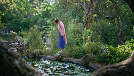 magical woman walking forest lake wearing original dress. girl looking on pond