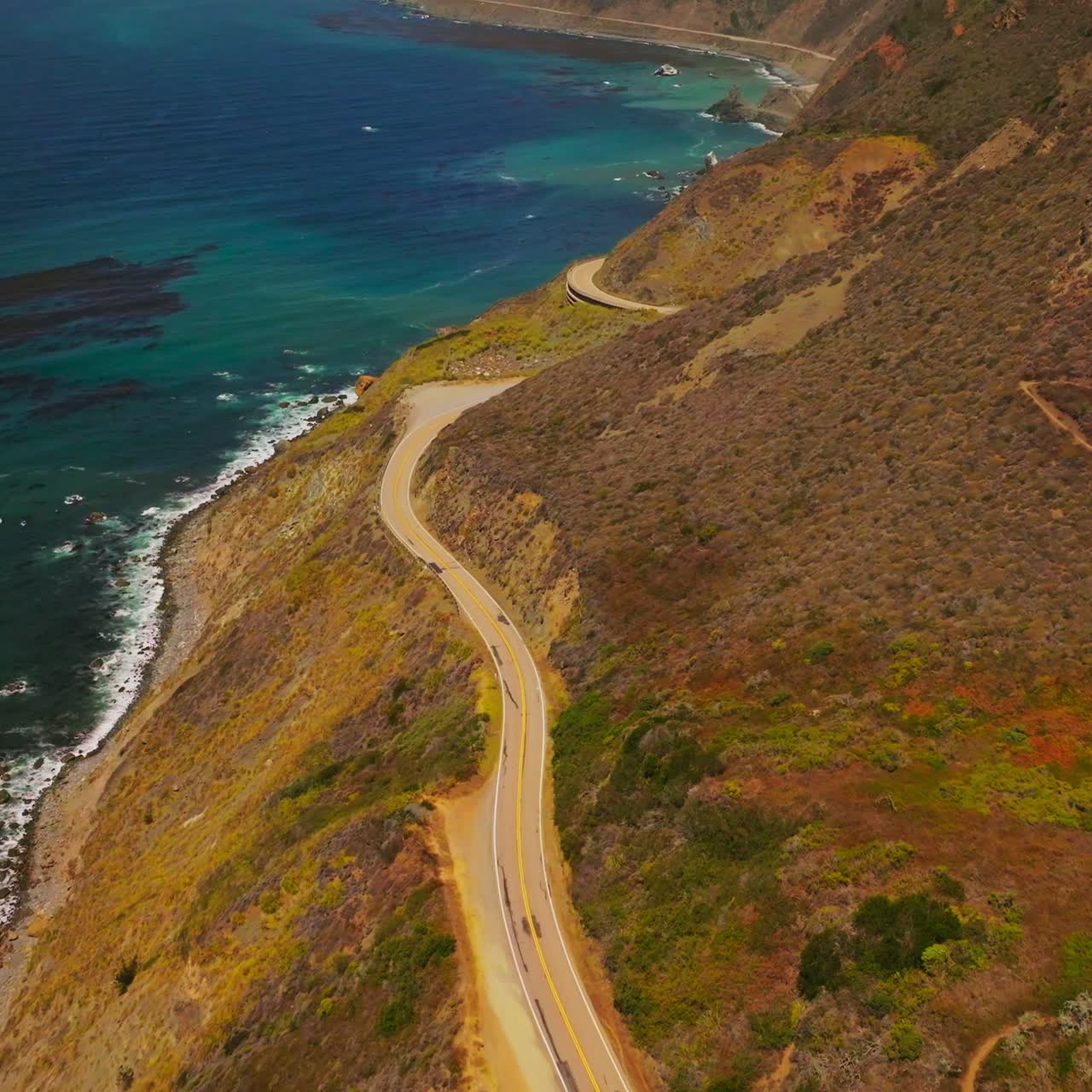 Footpath descending along the mount to the highway. Rocky shore of California with fantastic view of the ocean from above