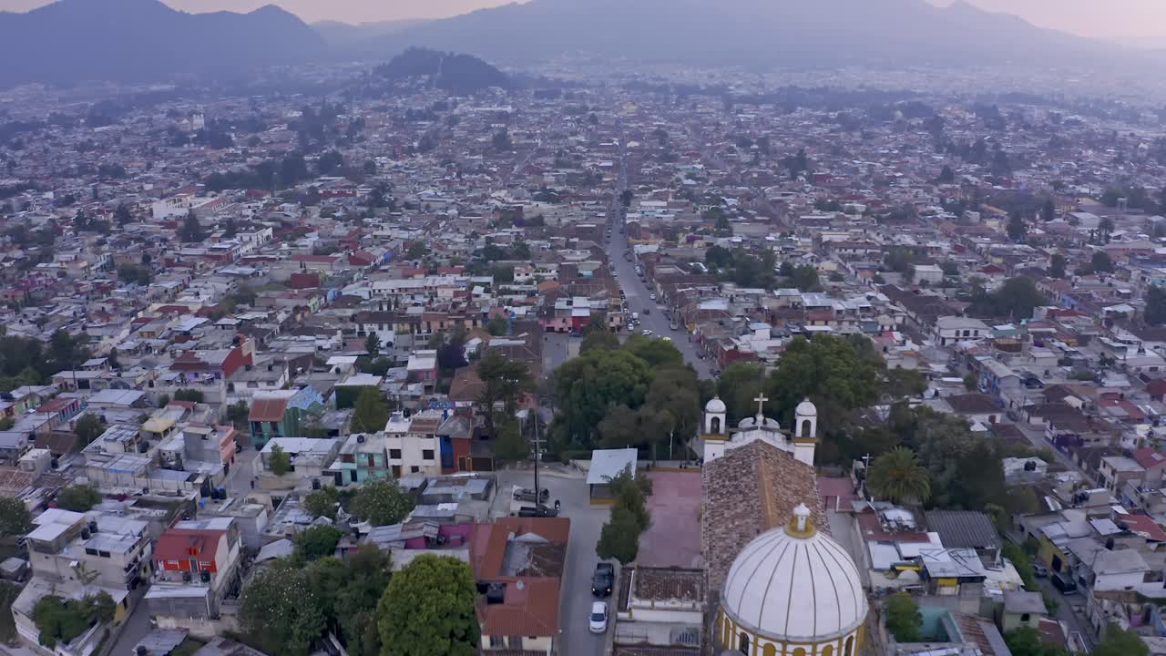 An aerial drone shot captures the charming colonial city of San Cristóbal de las Casas in Chiapas, Mexico, at sunset
