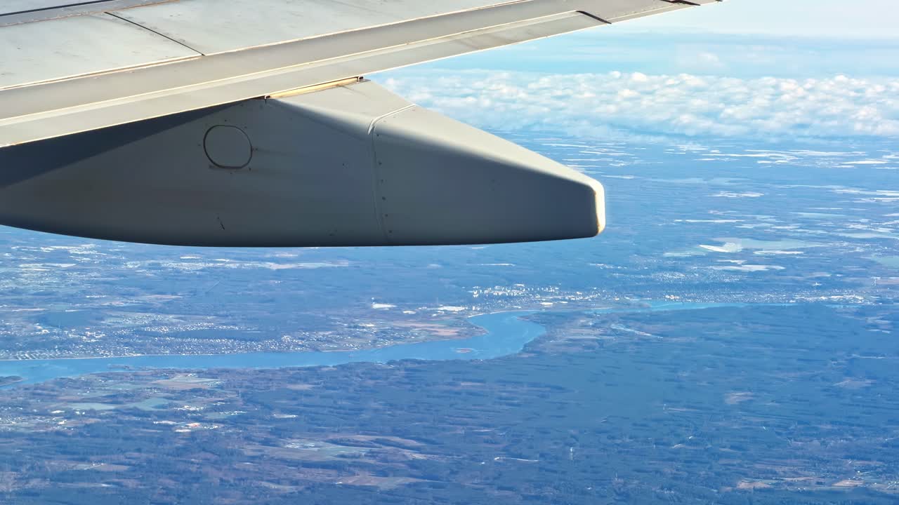 Vista di Riga dal finestrino di un aereo, con ala, cielo blu e nuvole