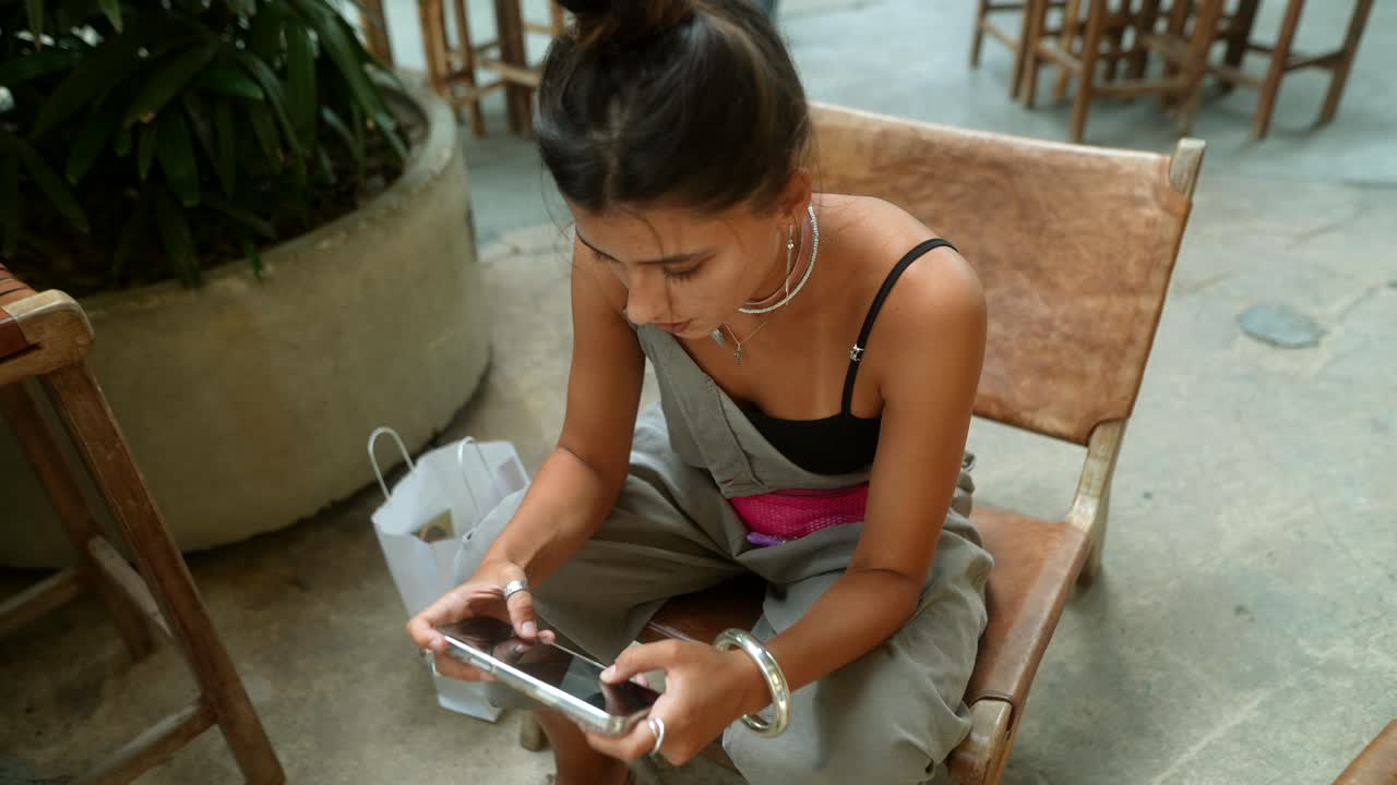 A woman using a mobile phone while sitting on a chair