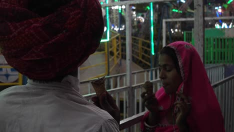 indian couple eating ice cream in traditional dresses at the pushkar mela, a carnival of rajasthan, india