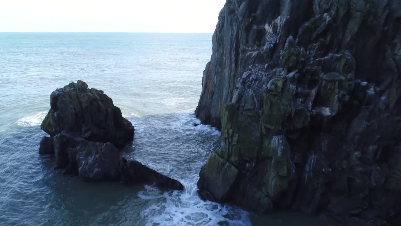 A fly through shot between sea stumps next to a cliff giving detail to the coastal erosion whilst revealing the vast ocean in Ireland