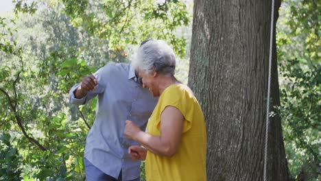 senior african american husband and mixed race wife dancing and laughing together in the garden