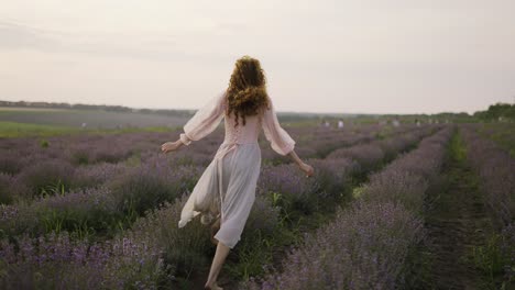 beautiful woman with a pink dress running joyfully through a lavender field