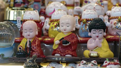 Colorful-figurines-of-Buddhist-monks-on-display-at-Ben-Thanh-Market,-Saigon