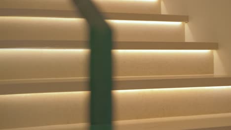 panning shot revealing brightly lit white stairs with a glass rail inside a mansion