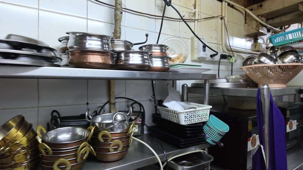 Static medium shot of organized metal pots, copper bowls, and kitchenware on industrial shelves.