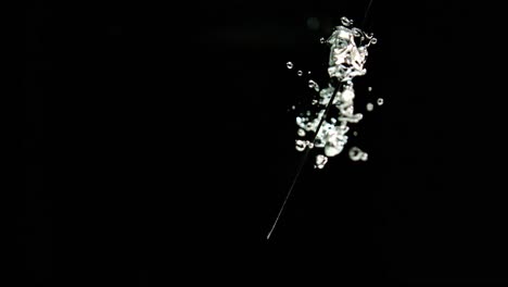 super slow motion of knife cutting through water on black background