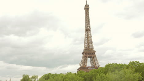 la parte superior de la torre eiffel de pie alto con árboles en la base en un día nublado