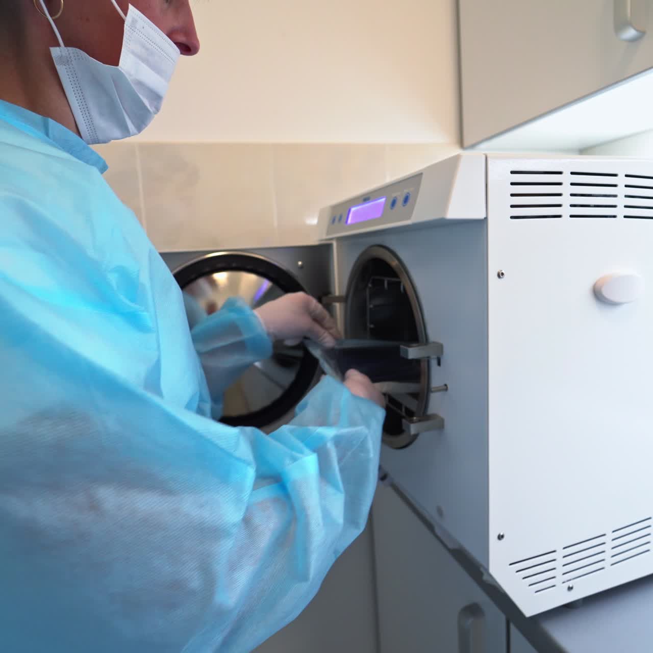 Female nurse takes sterile instruments out of sterilizer. Special equipment for preparation tools to various dental procedures
