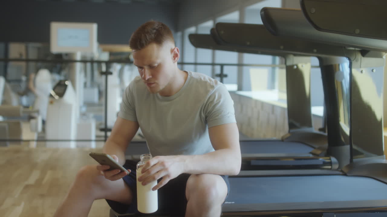 Man Using Phone while Resting in Gym